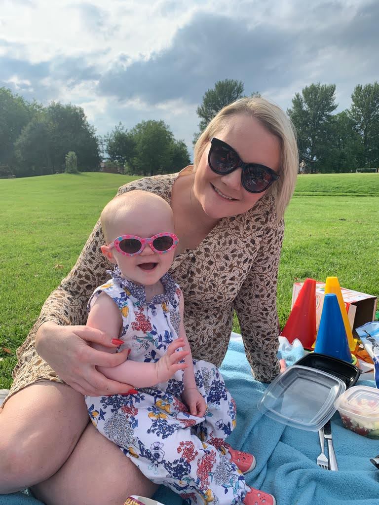Jemma Munford Toddler Sleep Expert sitting in a park with smiling toddler wearing sunglasses