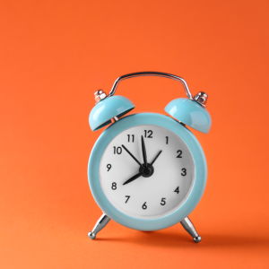 Light blue alarm clock on orange background